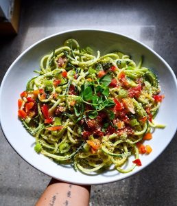 A woman holding a veggie pasta dish