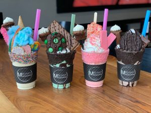 Four milkshakes on a wooden table