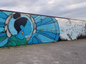 A mural of a woman blowing leaves into the air