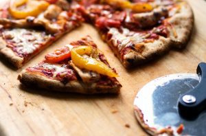 Homemade pizza and pizza cutter on a cutting board