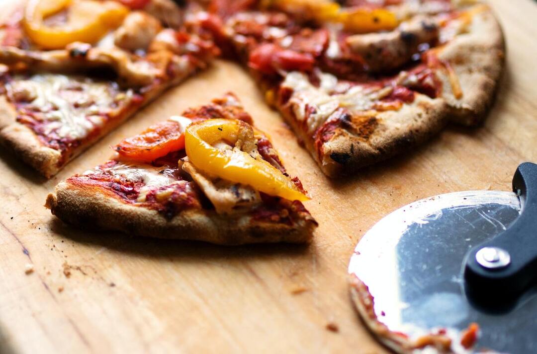 Homemade pizza and pizza cutter on a cutting board