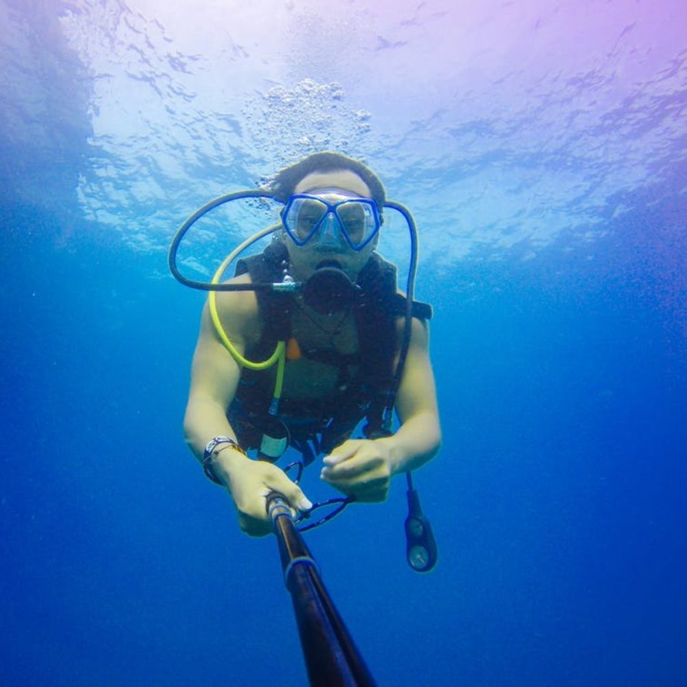 diver taking a selfie with a selfie stick while scuba diving