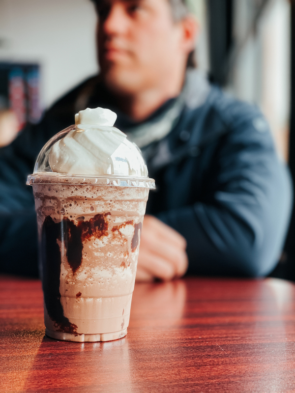 an iced coffee drink on a table with a man in the background