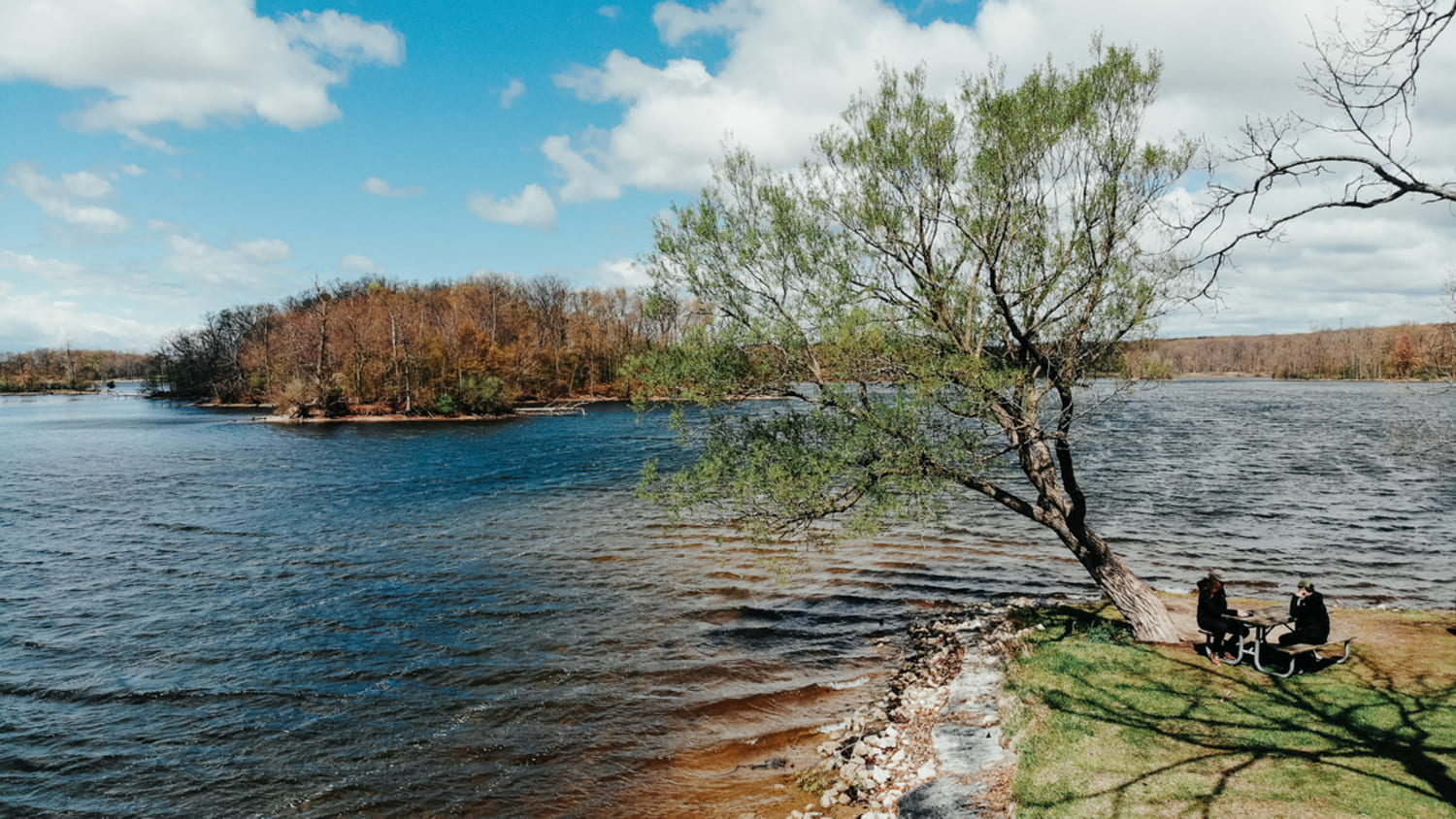 an aerial shot of a lake and a picnic table