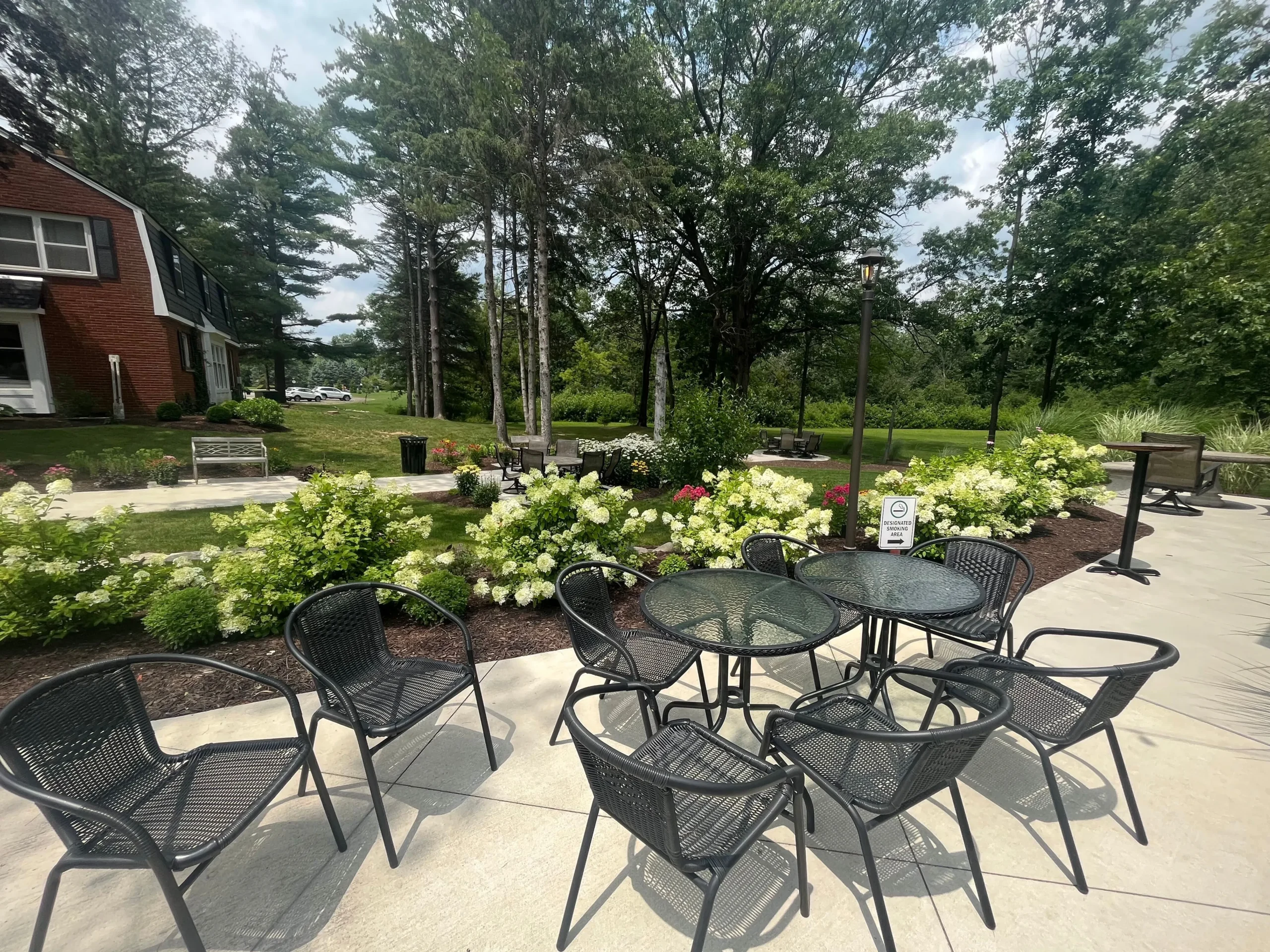Tandale Nature Barn outside patio on a sunny day with black metal chairs and flowers.