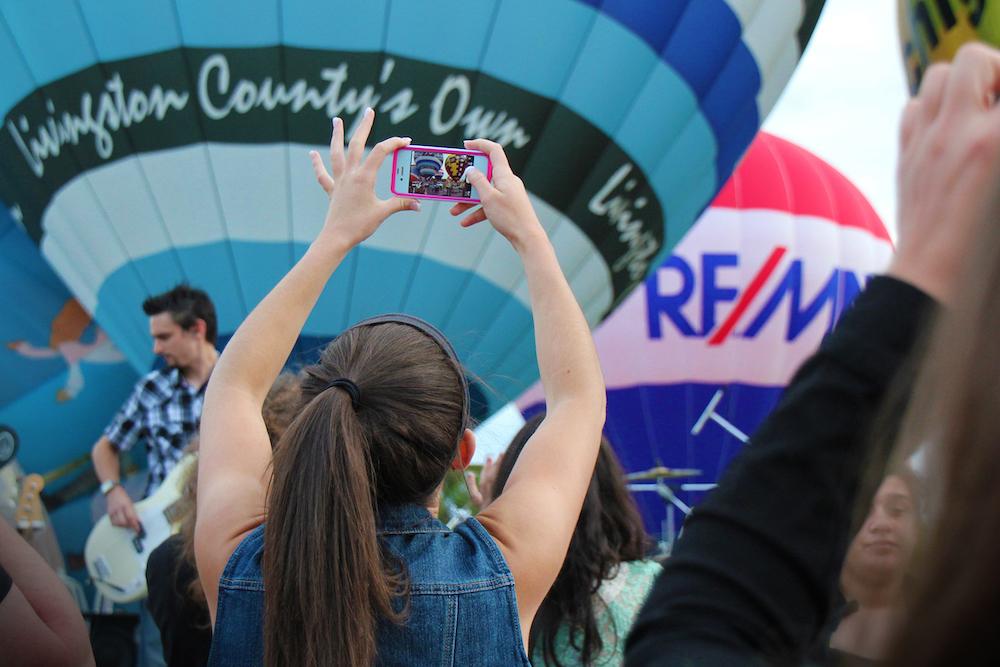 Girl taking a picture of the Howell Balloon Festival hot air balloons