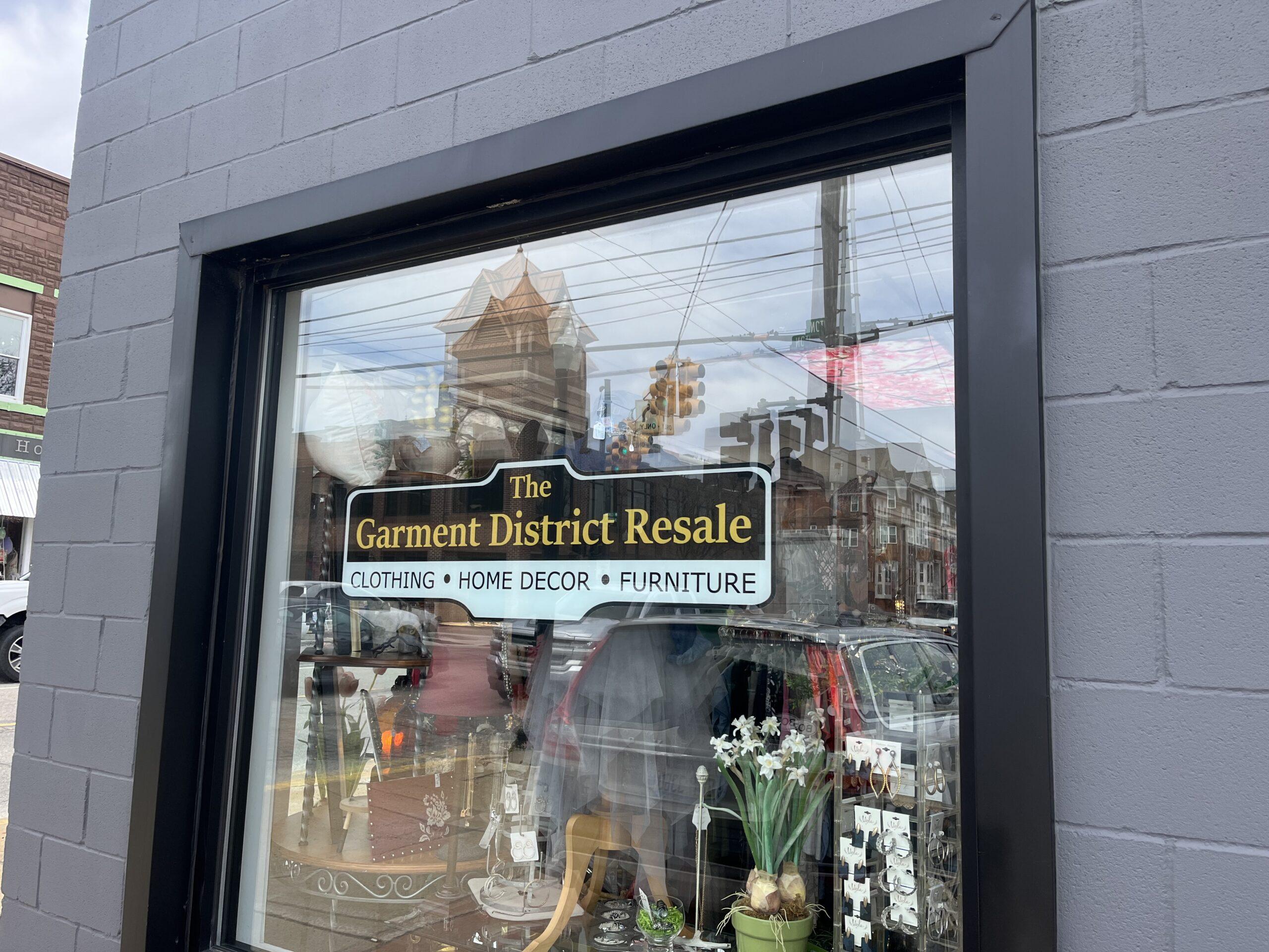 Garment District Resale storefront sign on window against grey cinderblock building.