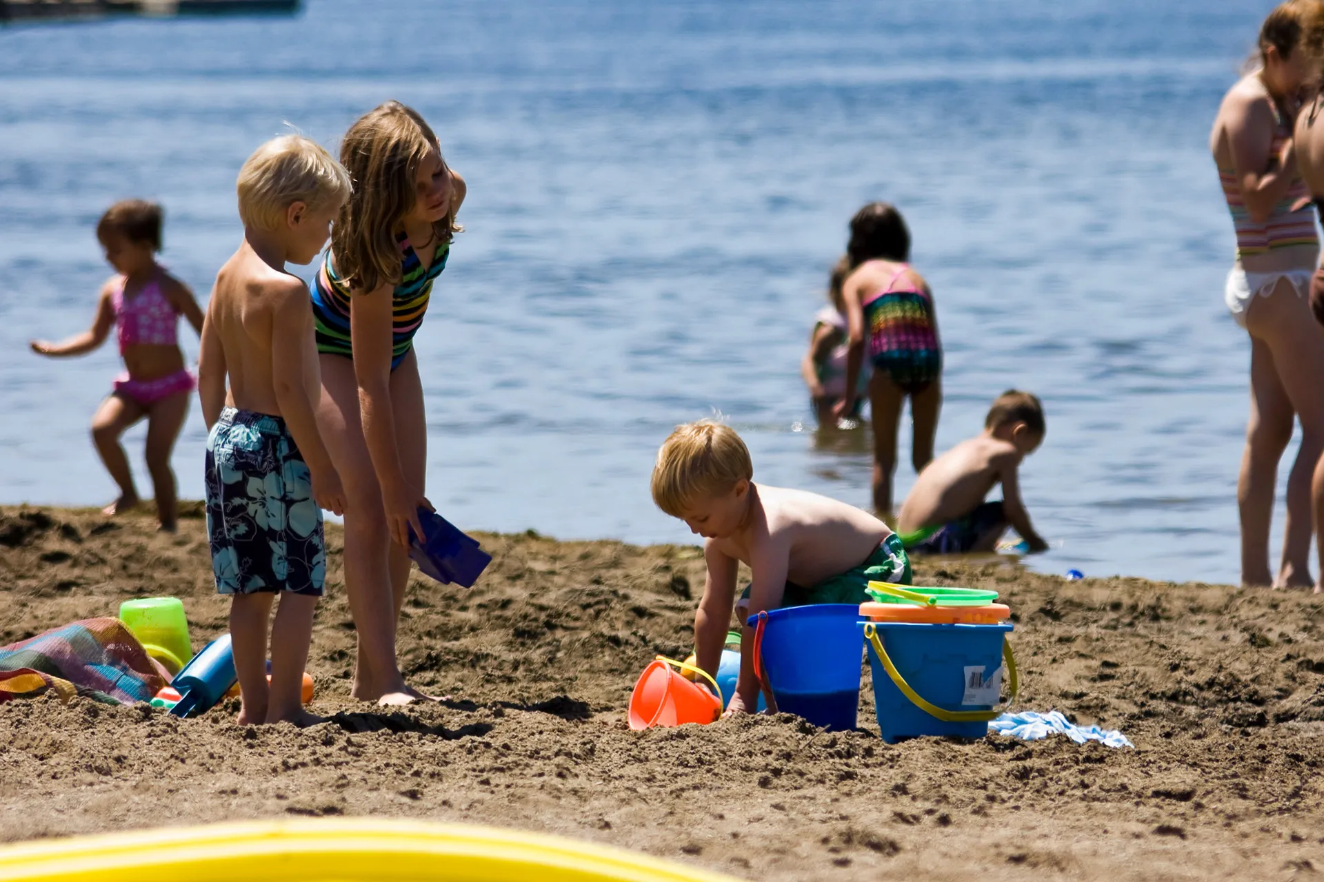 kids playing on the beach with buckets and water