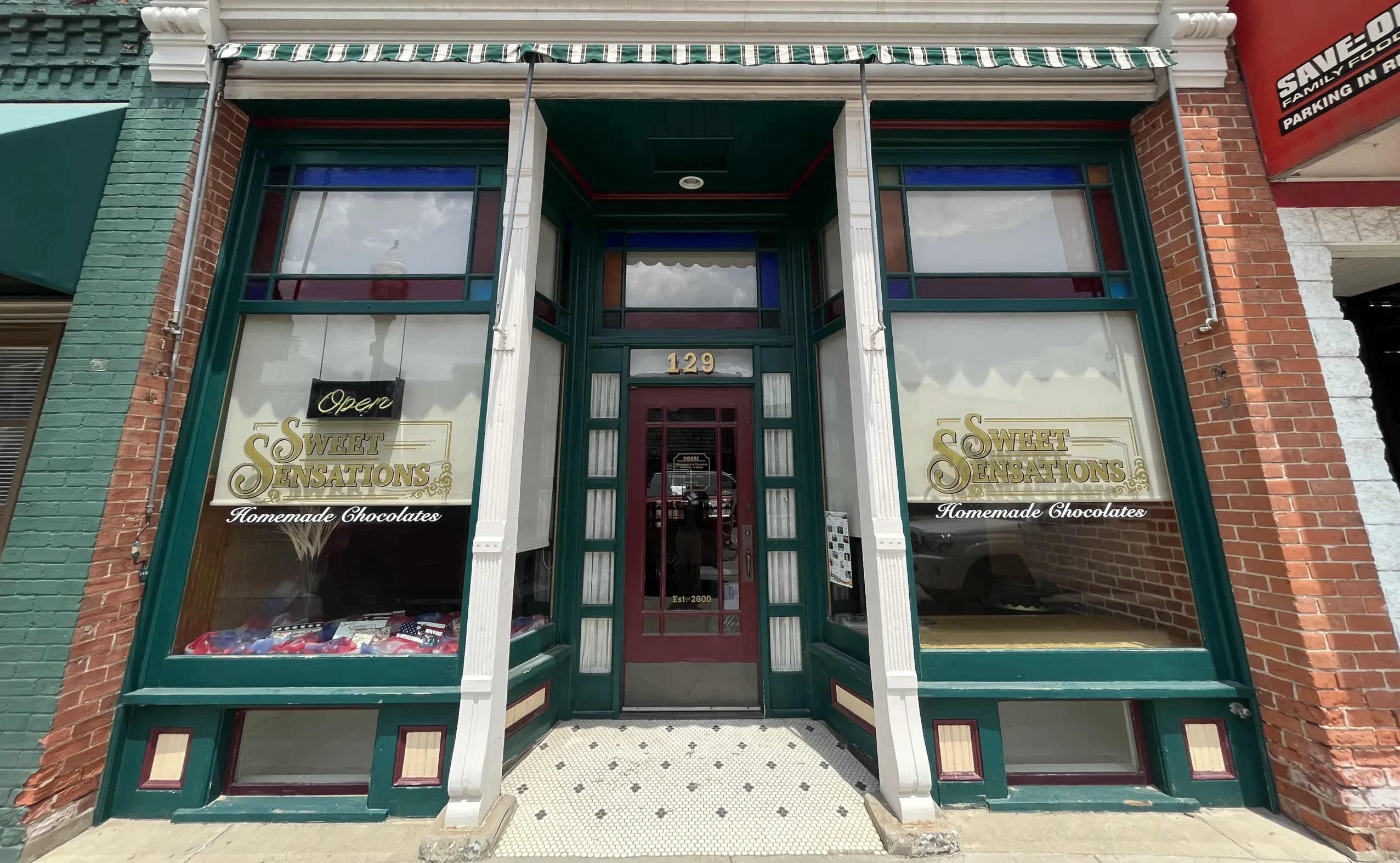 Sweet Sensations green detailed storefront with windows and gold sign.