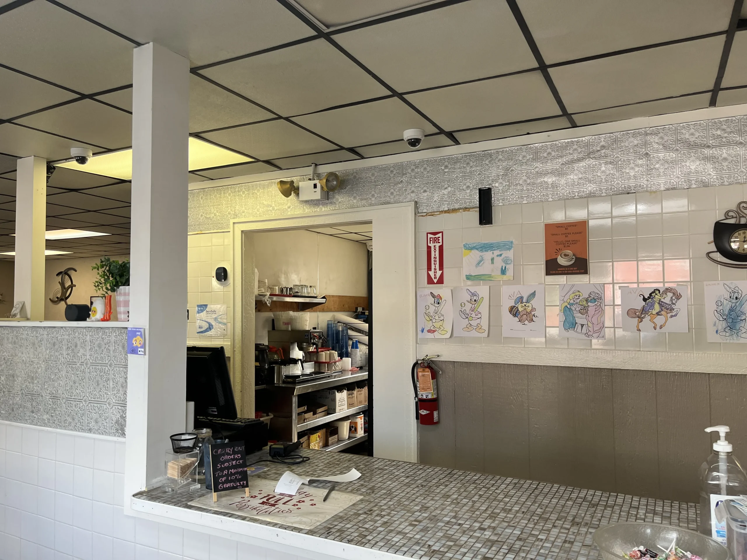 Whitmore Coney check out counter and register with drawings behind.