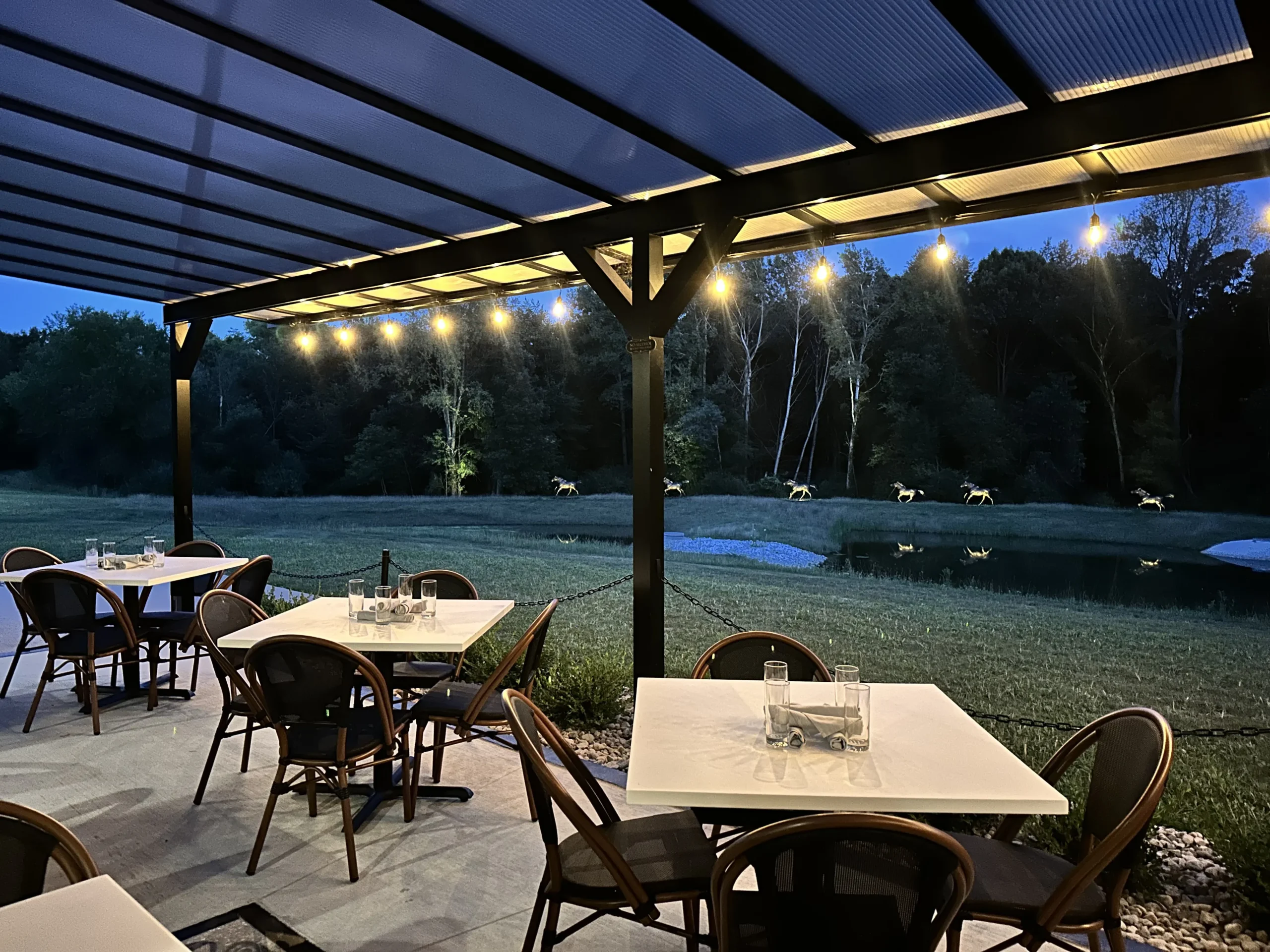 Horse Feathers Kitchen and Cocktails outdoor dining space at night with illuminated tables.