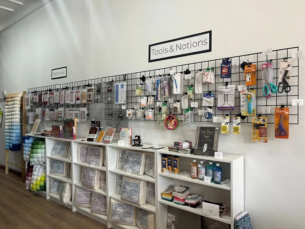 Alyssum Patch Contemporary Quilt Shop tool wall with items on racks and shelves.