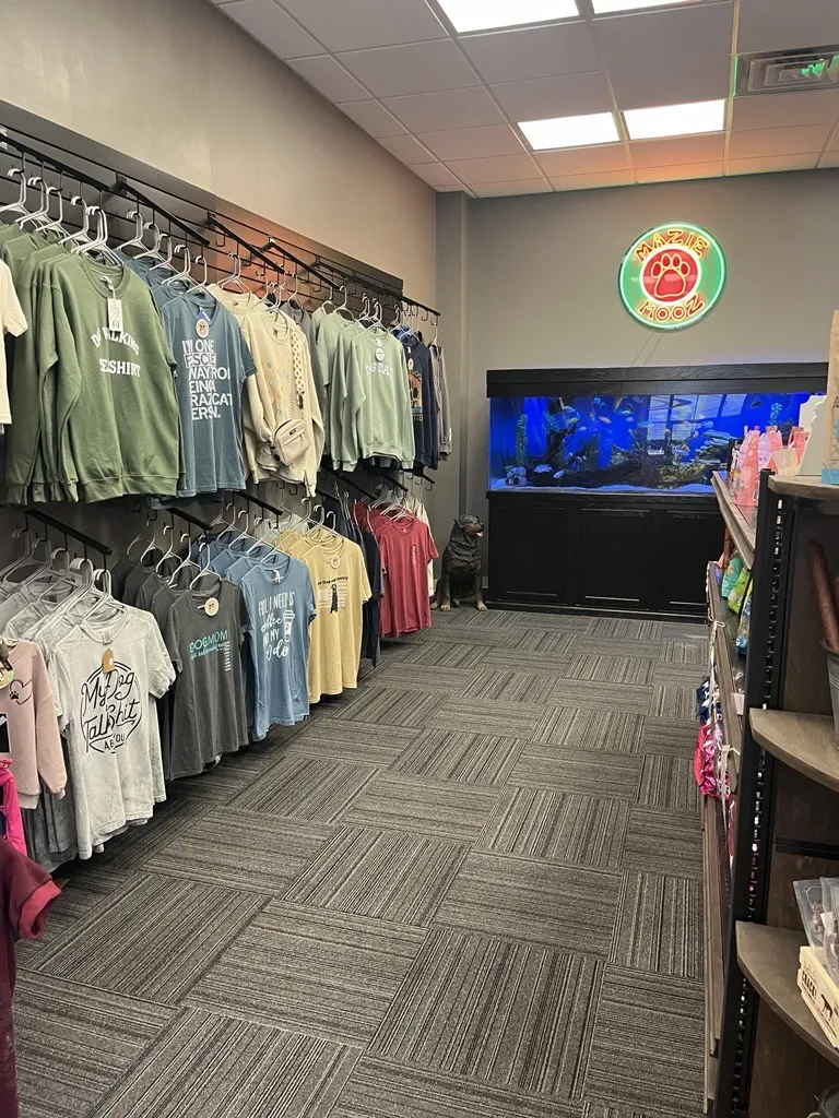 Mazie Mooz shirts for sale along wall with large fishtank at the back at pet store in downtown Brighton.