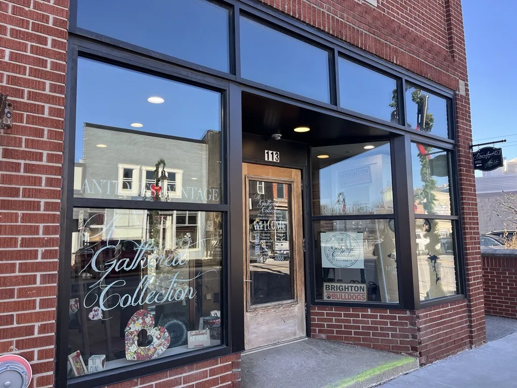 A Gathered Collection storefront with windows and red brick in downtown Brighton.